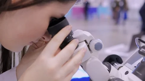 A scientist is conducting a thorough examination of various samples using a Stock Footage 296732416