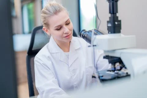 Scientist conducts research in laboratory using microscope during daytime Stock Photos