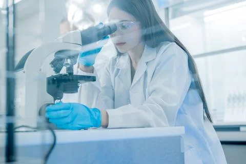 Scientist conducts research using microscope in modern laboratory setting d.. Stock Photos