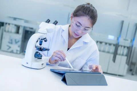 Scientist conducts research using a microscope and tablet in a modern labor.. Foto stock