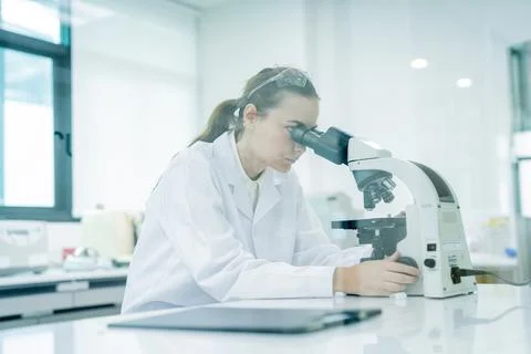 Scientist conducts research while looking through a microscope in a modern .. Stockfoto's