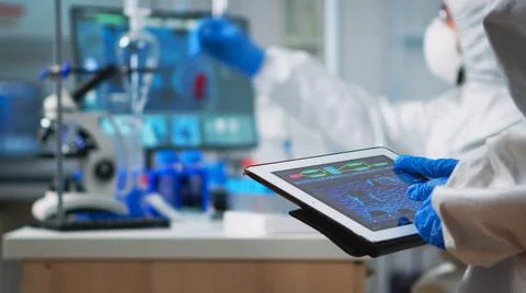 Scientist in coverall analyzing virus evolution looking on digital tablet Stock Photos
