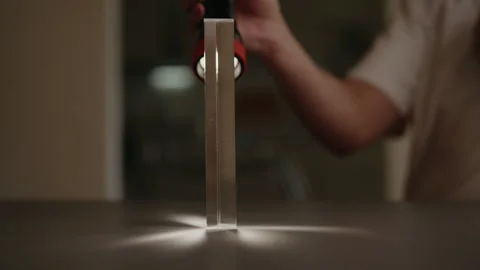 Scientist directing beam of light at triangular glass prism, causing light to Stock Footage 311569880