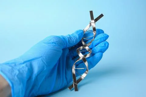 Scientist with DNA molecular chain model made of metal on light blue backgr.. Foto stock