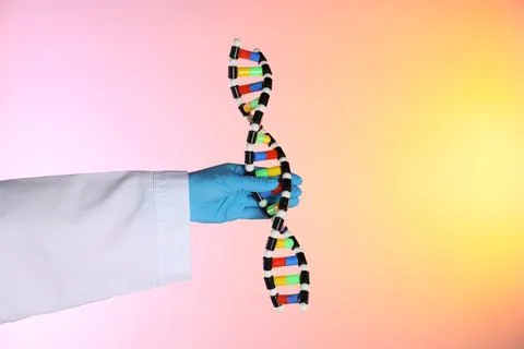 Scientist with DNA structure model on color background, closeup 스톡 사진