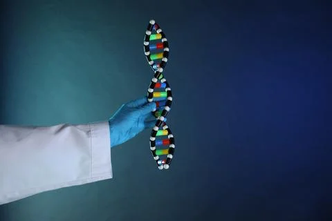 Scientist with DNA structure model on dark blue background, closeup 写真素材