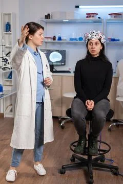 Scientist doing brain analysis using headset with sensors on patient Stock Photos