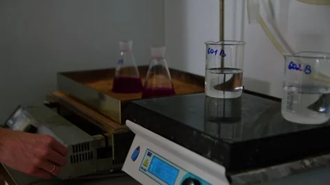 A scientist doing research with beakers with pink liquid in the laboratory Stockbeeldmateriaal 275077115