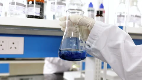 Scientist doing science experiment in a beaker. flask titration with colorful Stock Footage 273156514