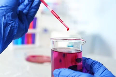 Scientist dripping reagent into beaker with sample in chemistry laboratory, c Foto stock