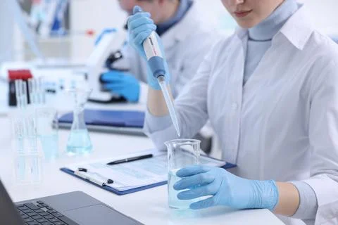 Scientist dripping sample into beaker in laboratory, closeup Foto stock