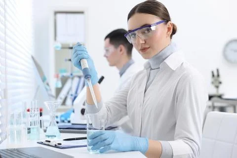 Scientist dripping sample into beaker in laboratory Foto stock
