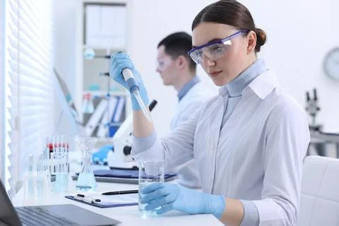 Scientist dripping sample into beaker in laboratory Foto stock
