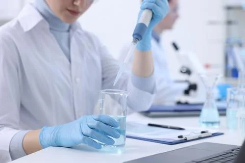 Scientist dripping sample into beaker in laboratory, closeup Foto stock