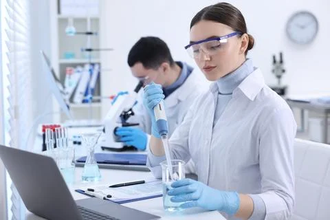 Scientist dripping sample into beaker in laboratory Foto stock