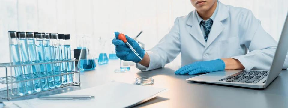 Scientist drop precise amount of liquid from pipette into test tube. Neoteric Stock Photos