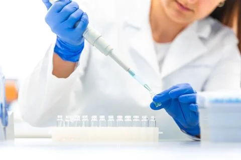 Scientist with dropper dripping liquid into a test tube in scientific laboratory Фото