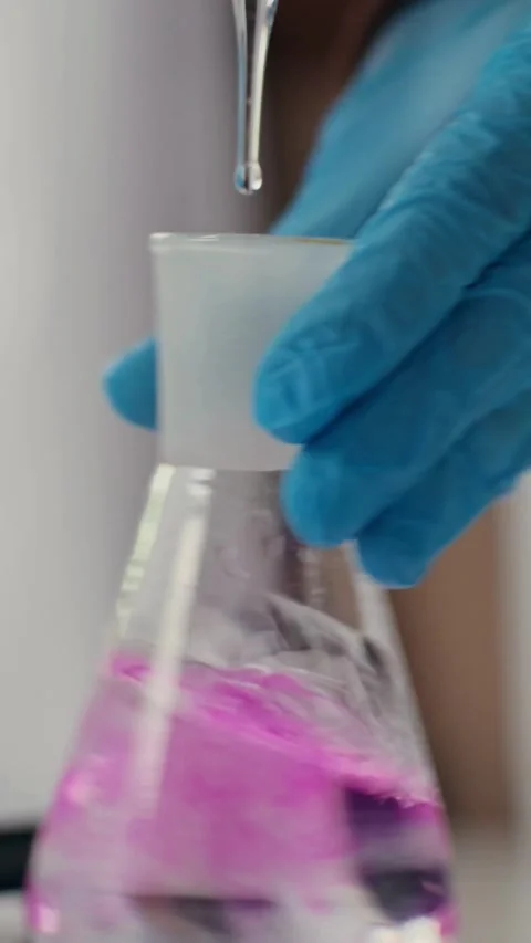 Scientist drops liquid into flask causing pink color change 스톡 동영상 331775135