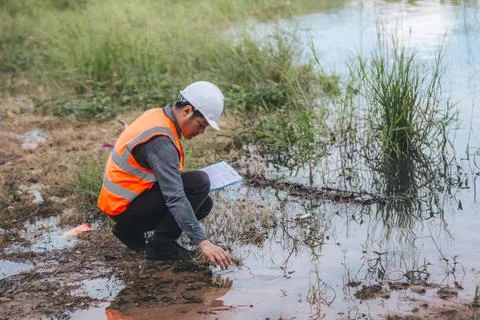 Scientist Ecologist taking a water sample and reading ph value at river. Wa.. Stock Photos