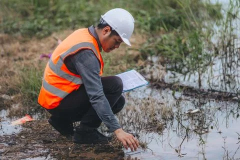 Scientist Ecologist taking a water sample and reading ph value at river. Wa.. Stock Photos