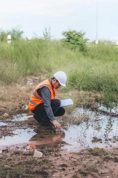 Scientist Ecologist taking a water sample and reading ph value at river. Wa.. Stock Photos
