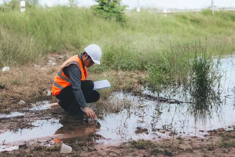 Scientist Ecologist taking a water sample and reading ph value at river. Wa.. Stock Photos