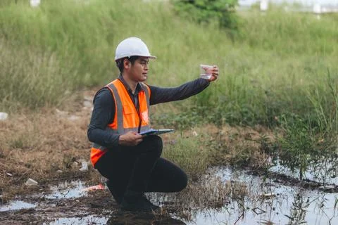 Scientist Ecologist taking a water sample and reading ph value at river. Wa.. Stock Photos