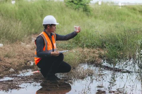 Scientist Ecologist taking a water sample and reading ph value at river. Wa.. Stock Photos
