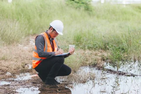 Scientist Ecologist taking a water sample and reading ph value at river. Wa.. Stock Photos