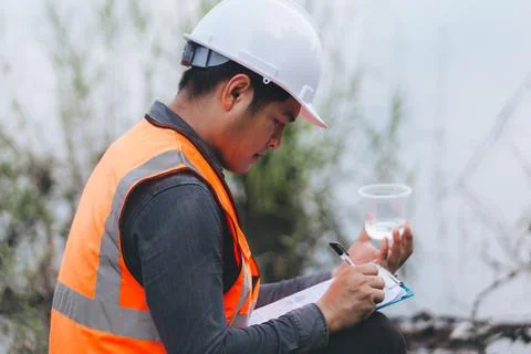 Scientist Ecologist taking a water sample and reading ph value at river. Wa.. Stock Photos