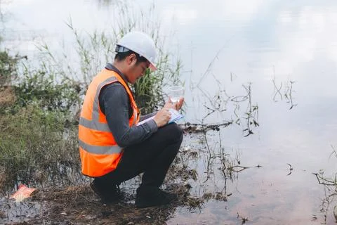 Scientist Ecologist taking a water sample and reading ph value at river. Wa.. Stock Photos