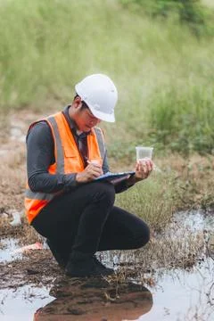 Scientist Ecologist taking a water sample and reading ph value at river. Wa.. Stock Photos