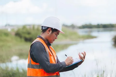 Scientist Ecologist taking a water sample and reading ph value at river. Wa.. Stock Photos