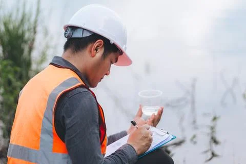 Scientist Ecologist taking a water sample and reading ph value at river. Wa.. Stock Photos