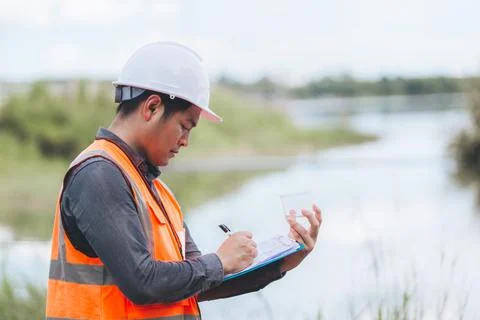Scientist Ecologist taking a water sample and reading ph value at river. Wa.. Stock Photos