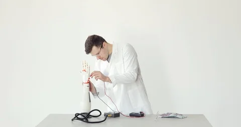 Scientist engineer connects and configures robotic prosthesis hand on the table Stock Footage 106220865