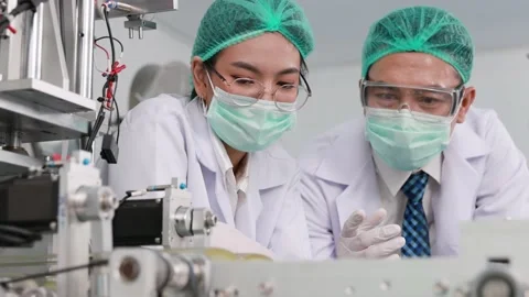Scientist engineer or doctor in face mask discussion at medical mask production  Stock Footage 158468947