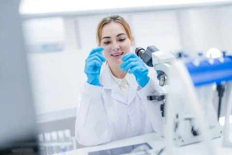 Scientist examines sample with microscope in laboratory during daytime work.. Stock Photos