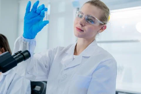 Scientist examines sample under microscope in modern laboratory during daylig Stock Photos