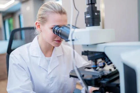 Scientist examines samples using a microscope in a modern laboratory during.. Stock Photos