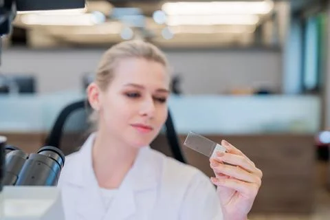 Scientist examines slide under microscope in contemporary laboratory settin.. Stock Photos