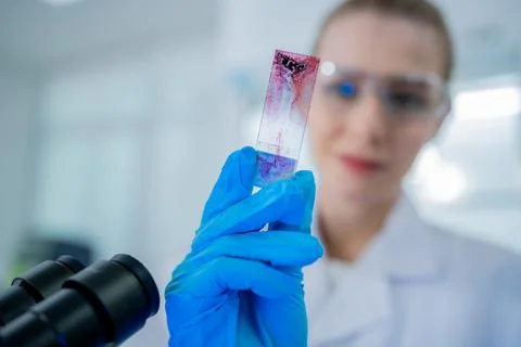 Scientist examines slide under microscope in modern laboratory setting, sho.. Stock Photos