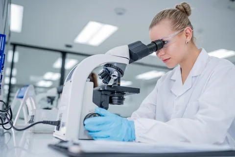 Scientist examines specimens through a microscope in a laboratory setting d.. Stock Photos