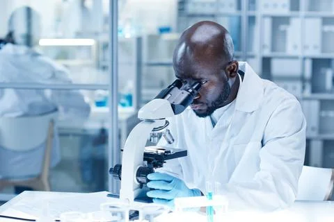 Scientist examining the new virus with microscope Stock Photos