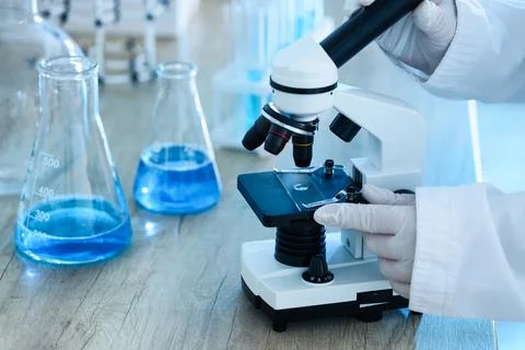 Scientist examining sample under microscope in laboratory Stock Photos