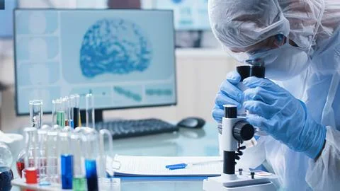 Scientist examining sample under microscope in lab Фото