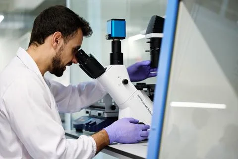 Scientist examining samples through an inverted microscope in a laboratory Фото