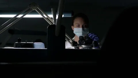 Scientist examining samples through a microscope 動画素材 77078731