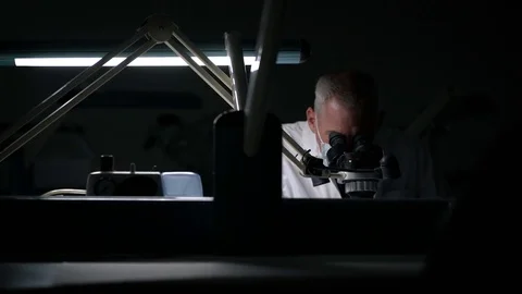 Scientist examining samples through a microscope 動画素材 77078743