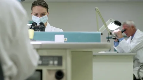 Scientist examining samples through a microscope 動画素材 77096658